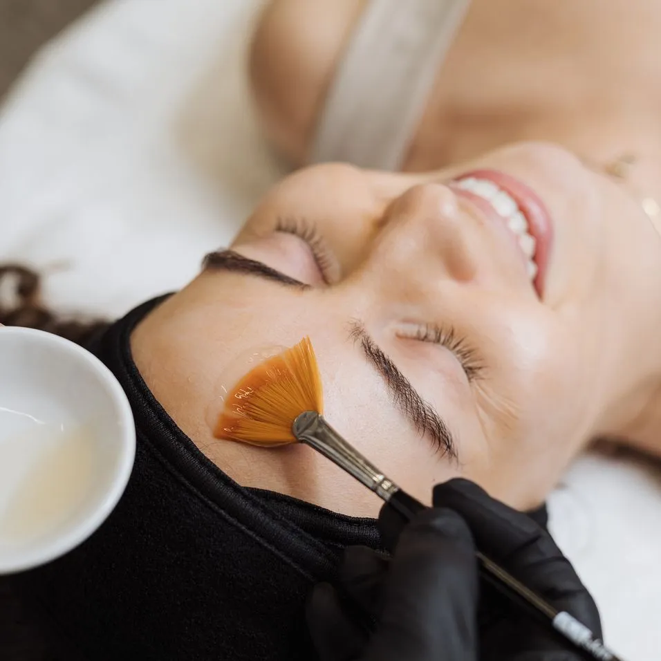 A woman getting her face painted with orange.